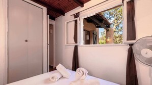 Une chambre à coucher avec un lit, une fenêtre, un ventilateur et une porte.