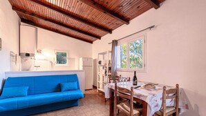Une pièce chaleureuse avec un canapé bleu, une table à manger en bois et un plafond avec des poutres apparentes.