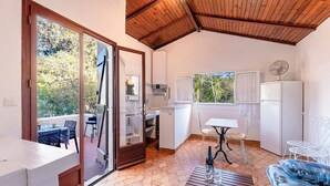 A compact kitchen with white cabinets, a dining area with a table and chairs, and a wooden ceiling. - Villa "RoccaPina " 35m² - 2/4 pers, Rondinara, Bonifacio (Bonifacio)