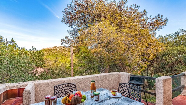 An outdoor dining area with a table set for two, surrounded by stone walls and a view of trees. - Villa "RoccaPina " 35m² - 2/4 pers, Rondinara, Bonifacio (Bonifacio)