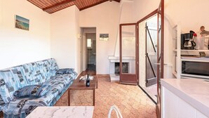 A cozy living room with a patterned sofa, a wooden coffee table, and a fireplace. - Villa "RoccaPina " 35m² - 2/4 pers, Rondinara, Bonifacio (Bonifacio)