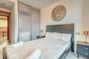 Ein modernes Schlafzimmer mit einem großen Bett, einem Schiebetürenschrank, einer runden Wanddekoration und einem Nachttisch mit Lampe.