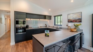 A modern kitchen with dark cabinetry, a central island, and a large window.