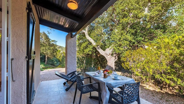 An outdoor patio with a table set for two, surrounded by chairs, and a view of trees and a road. - Villa "Lavezzi" 35m² - 2/4 pers, Rondinara, Bonifacio (Bonifacio)
