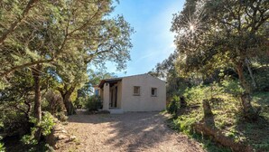 A small, single-story building with a gravel driveway leading to a wooden door. - Villa "Lavezzi" 35m² - 2/4 pers, Rondinara, Bonifacio (Bonifacio)