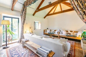 A cozy room with a sofa, a bench, a table, and a window with curtains. - 1 Bed in St. Austell (oc-b33396) (Pentewan Valley)