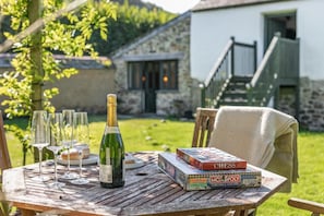 A wooden table with a bottle of champagne, glasses, and board games. - 1 Bed in St. Austell (oc-b33396) (Pentewan Valley)