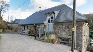 A stone house with a sloped roof, a visible chimney, and a gravel driveway. - 3 Bed in Totnes (oc-bcplym) (Broadhempston)