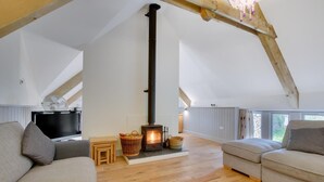 A loft-style living room with a wood-burning stove, two sofas, a television, and a stone wall. - 3 Bed in Totnes (oc-bcplym) (Broadhempston)