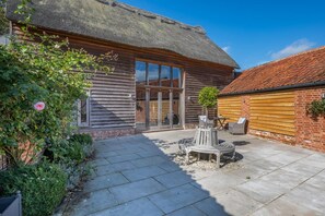 A rustic building with a thatched roof, a wooden exterior, and a patio area with outdoor seating. - 7 Bed in Ellough (oc-g33283) (Ellough)