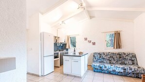 Un espacio habitable compacto con kitchenette, un sofá y zona de comedor.
