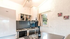 Una cocina compacta con refrigerador, estufa y pileta. Hay copas de vino sobre la encimera, y una botella de vino.