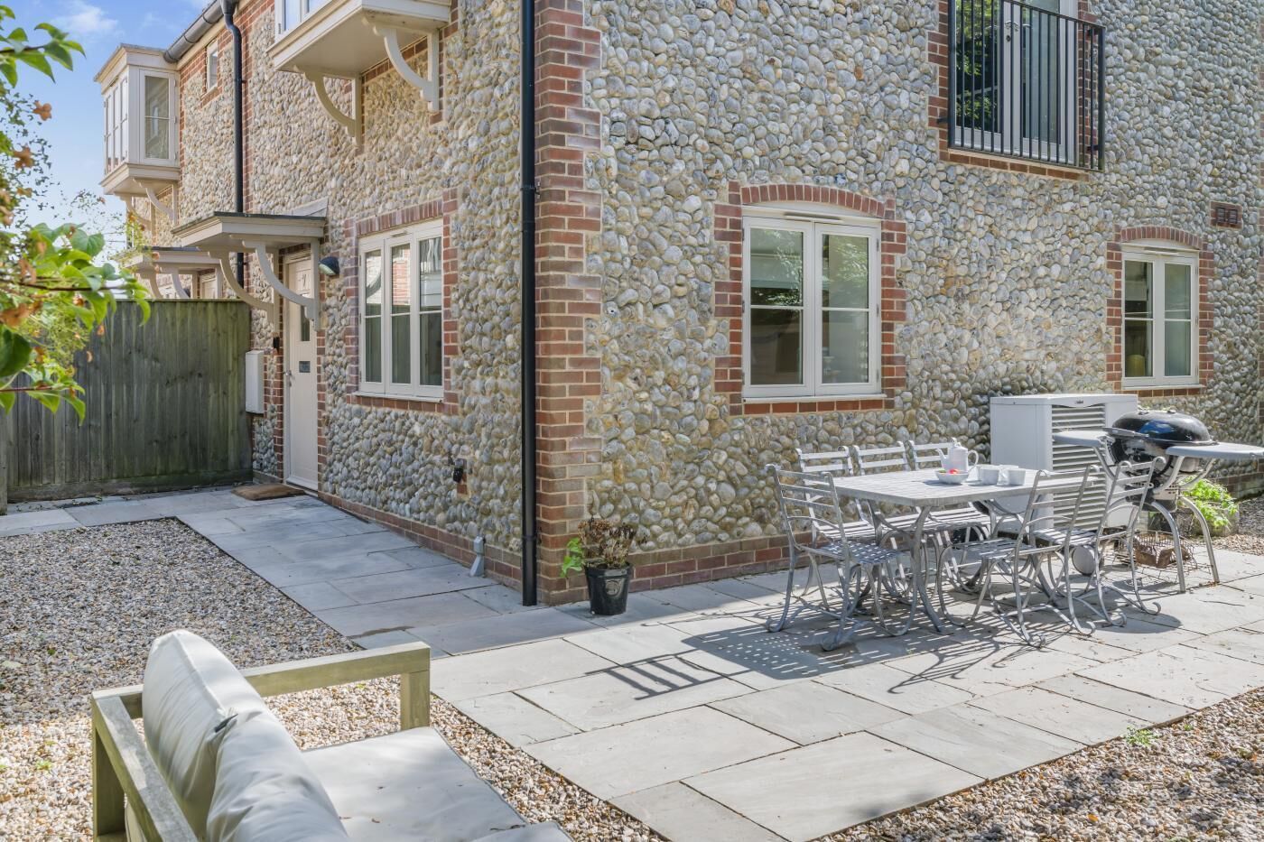 Una casa de piedra con un patio, mobiliario exterior y una zona de barbacoa.