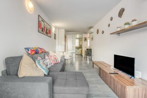 A modern living room with a grey sofa, a flat-screen TV, and a wooden console table. - Apartment 'Elegance Denia 21' with Shared Pool, Wi-Fi and Air Conditioning (Denia)