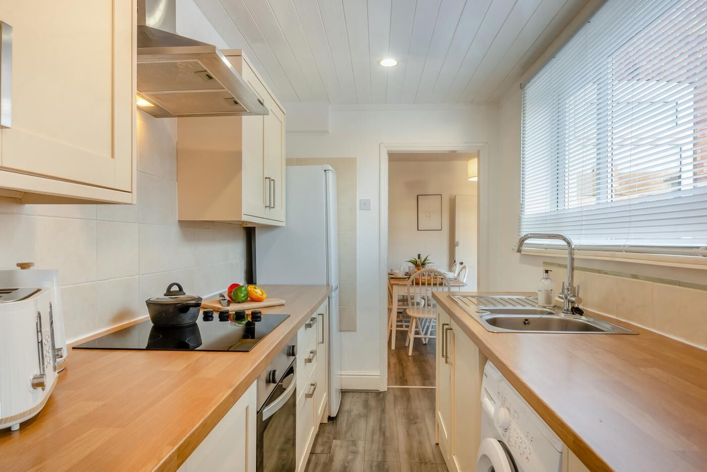 A compact kitchen with a stove, sink, and wooden countertops.