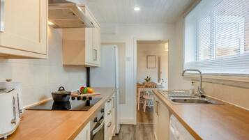 A compact kitchen with a stove, sink, and wooden countertops.