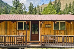 A rustic wooden cabin with a metal roof, a front door, and a sign that reads "The Big Horn." - Big Horn (cabin 3), BroadAxe on the River (Ravalli County)