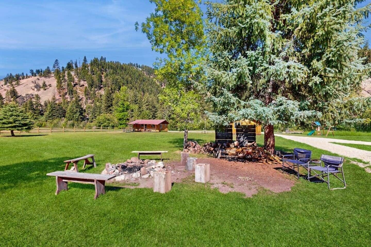 Un camping con mesas de picnic, un pozo de fuego y una cabaña pequeña.