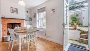 A dining area with a brick fireplace, white chairs, and a wooden table. - 2 Bed in West Lulworth (oc-j33448) (West Lulworth)