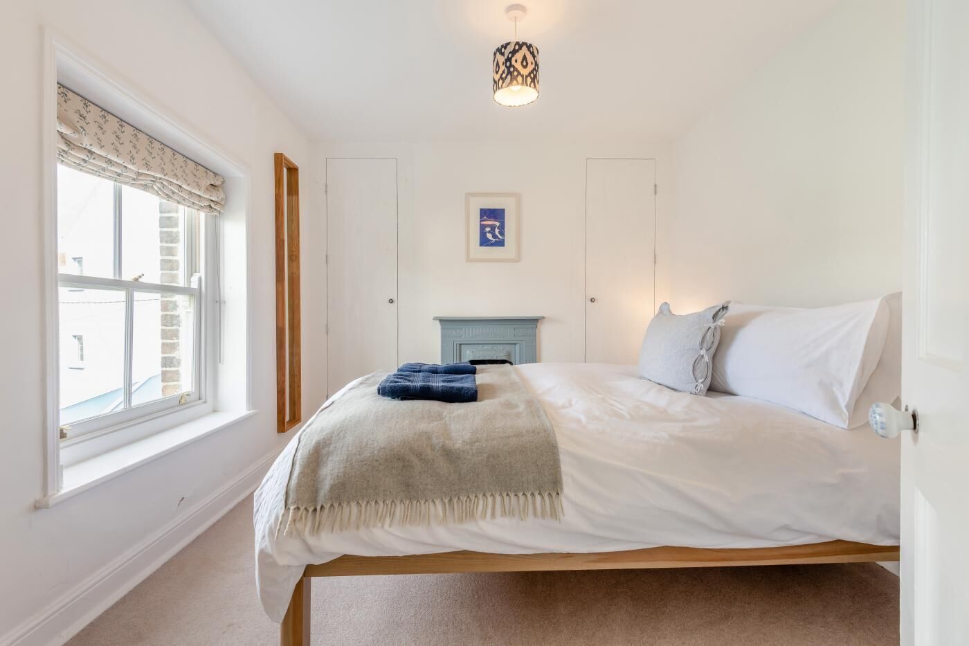 Une chambre à coucher avec un lit, une fenêtre, une cheminée et un luminaire au plafond.