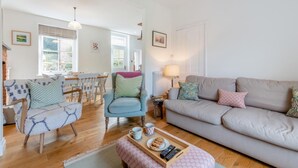 A cozy living room with a sofa, armchairs, a dining table, and a fireplace. - 2 Bed in West Lulworth (oc-j33448) (West Lulworth)