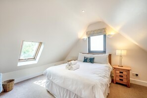 Un dormitorio con cama, mesita de noche, lámpara, ventana y tragaluz.