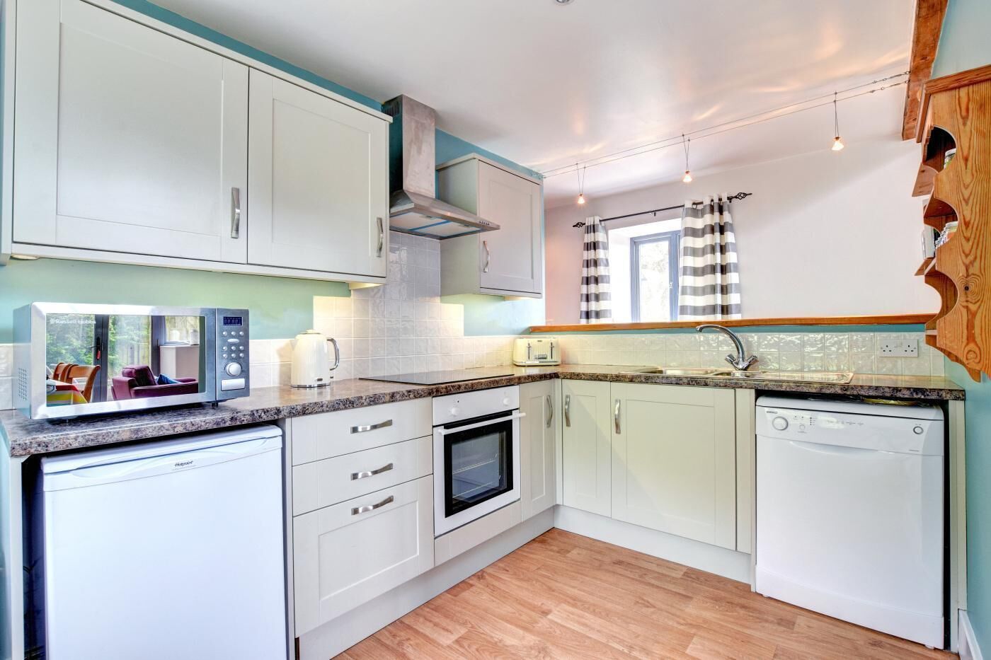 Een microgolfoven, een oven, een vaatwasser, kookgerei, borden en bestek