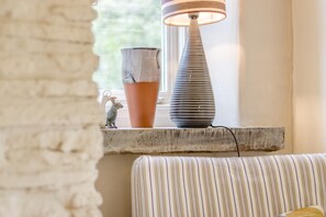Un rebord de fenêtre orné d’une lampe à rayures, d’un pot en terre cuite et d’une petite figurine.