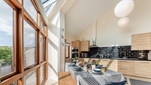 Una cuina moderna amb armaris de fusta, un salvasalls de rajola negra i una zona de menjador amb taula ben a punt per a quatre.