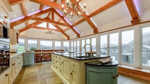 A spacious kitchen with a large island, wooden beams, and a view of the outdoors. - 10 Bed in Howtown (oc-w33505) (Ullswater)