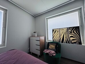 A bedroom with a bed, a dresser, a chair, and a window with blinds. - Nordic Home Bliss 2BR (Helsinki)