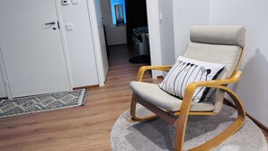 Une pièce avec un fauteuil à bascule en bois, un tapis à motifs et une porte donnant sur une autre pièce.