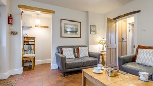 A living room with two sofas, a coffee table, a bookshelf, a lamp, and a door leading to another room. - 3 Bed in Wells-next-the-Sea (oc-h33452) (Wells-next-the-Sea)