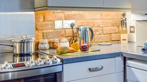 A kitchen with a stove, pots, jars, and vegetables on the counter. - 3 Bed in Wells-next-the-Sea (oc-h33452) (Wells-next-the-Sea)