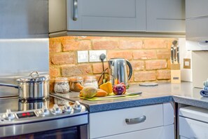 Una cocina con estufa, ollas, frascos y verduras sobre la encimera.