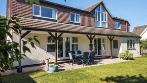 A two-story house with a covered patio, a dining area with chairs, and a small garden. - 4 Bed in Shaldon (oc-sunnhs) (Shaldon)