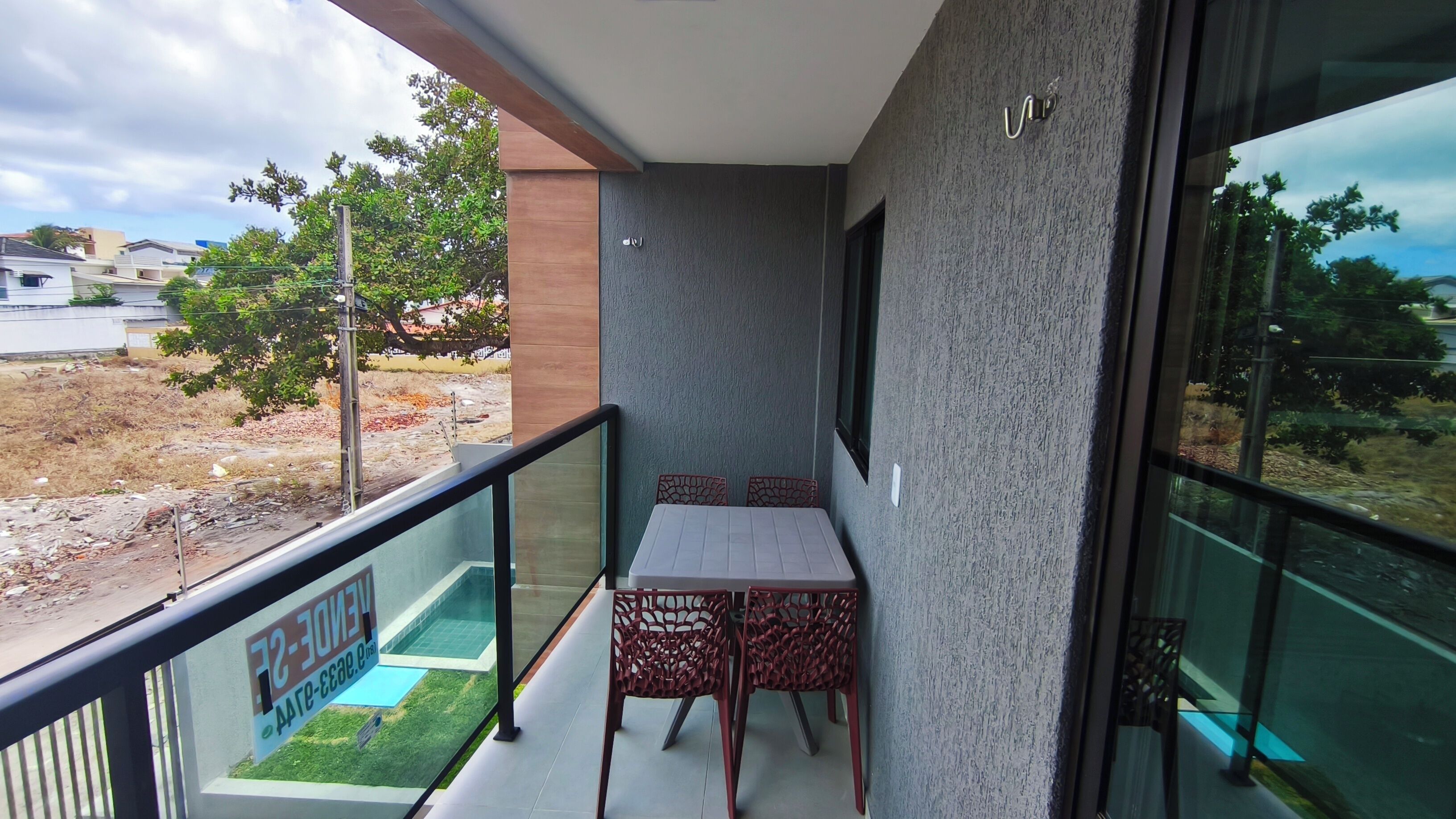 A balcony with a table and chairs, a glass barrier, and a view of a construction site.