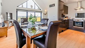 Een moderne eetruimte met een glazen tafel, zwarte lederen stoelen en uitzicht op het platteland.