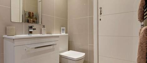 A modern bathroom with a toilet, sink, and mirror.