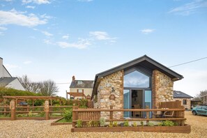A stone building with a wooden deck and a large window. - 1 Bed in Rhossili (oc-r33390) (Pilton)