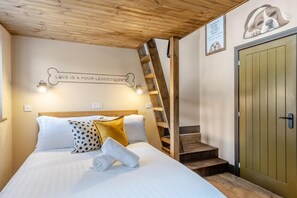 A bedroom with a bed, a wooden ladder, a green door, and a wall with a dog illustration and a quote. - 1 Bed in Rhossili (oc-r33390) (Pilton)