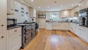 A modern kitchen with white cabinets, a black stove, and a wooden floor. - 4 Bed in Ellonby (oc-y33284) (Ellonby)