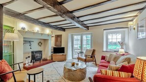 A cozy living room with a fireplace, a television, and a red sofa. - 4 Bed in Ellonby (oc-y33284) (Ellonby)