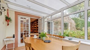 A dining area with a wooden table, chairs, a small white table, and a bookshelf. - 4 Bed in Ellonby (oc-y33284) (Ellonby)