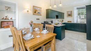 Une cuisine moderne avec des meubles de couleur turquoise, une table à manger en bois pour six personnes et des luminaires suspendus au-dessus.