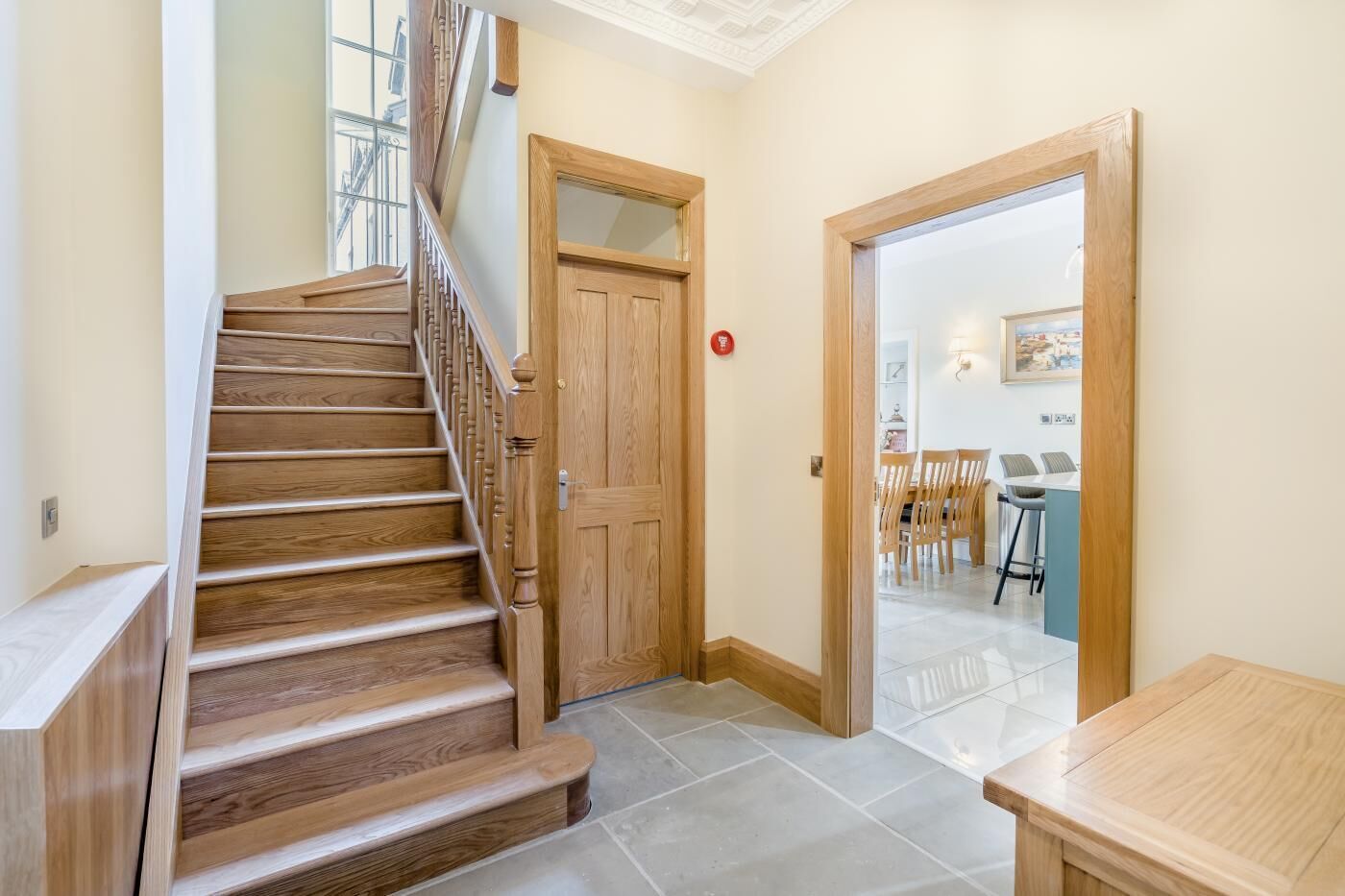 A wooden staircase leading to a room with a dining area visible through an open door.