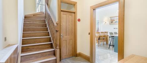 A wooden staircase leading to a room with a dining area visible through an open door.