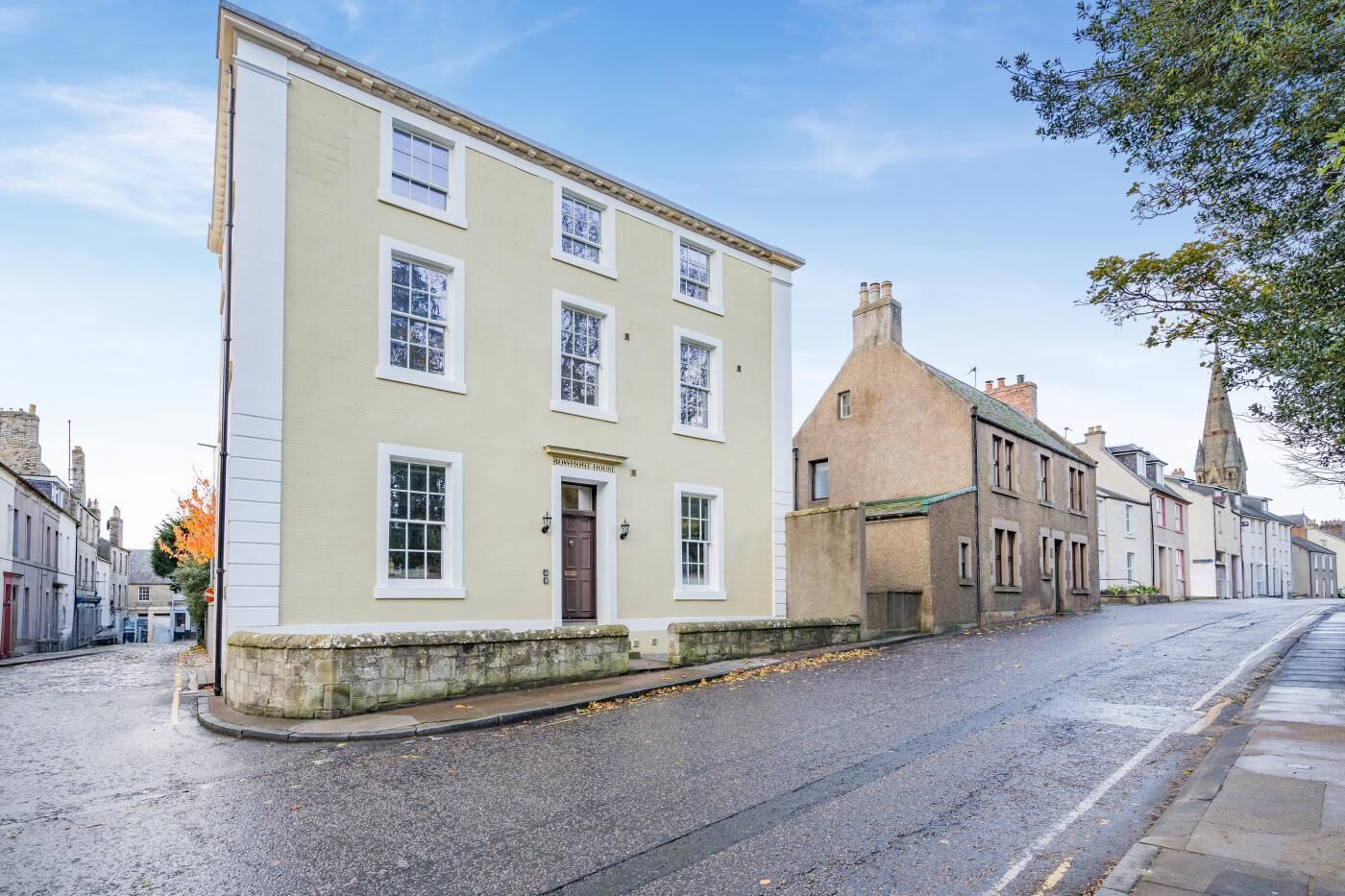 A traditional building with a prominent entrance and a corner location on a cobblestone street.