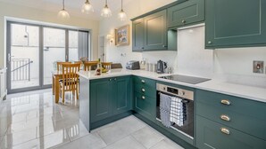 Une cuisine moderne avec des meubles de couleur turquoise, un îlot central et un coin repas doté de chaises en bois.