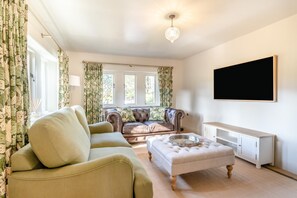 A living room with a sofa, armchair, ottoman, and a flat-screen TV mounted on the wall. - 3 Bed in Calver (oc-h33087) (Calver)
